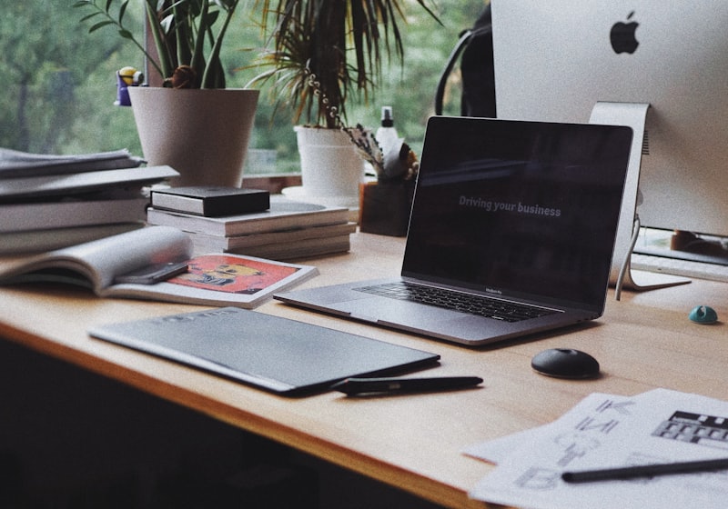 A tidy desk with a laptop, notebook and plants