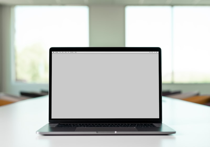 A laptop on a desk with daylight from a window behind